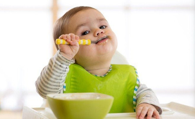 Các loại thực phẩm ăn dặm cho bé gồm rau củ quả tươi, ngũ cốc và bát đĩa trên nền gỗ