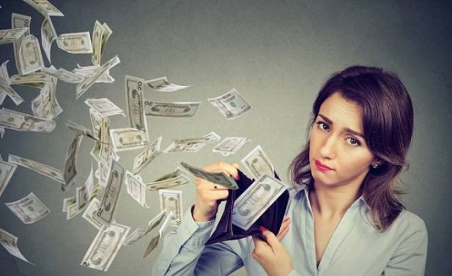 Người phụ nữ trẻ đang bối rối nhìn ví tiền rỗng sau khi chi tiêu quá đà