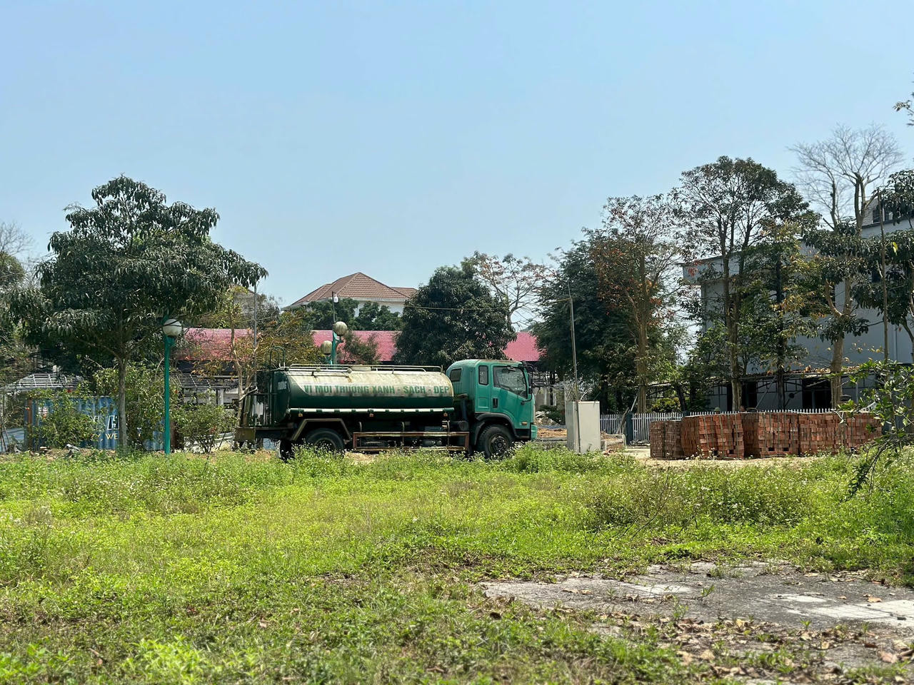 Chiếc xe thùng chở nước với thông điệp "vì môi trường xanh - sạch - đẹp" bị bỏ không trong Khu đô thị Xuân An, cho thấy sự thiếu quan tâm đến cảnh quan